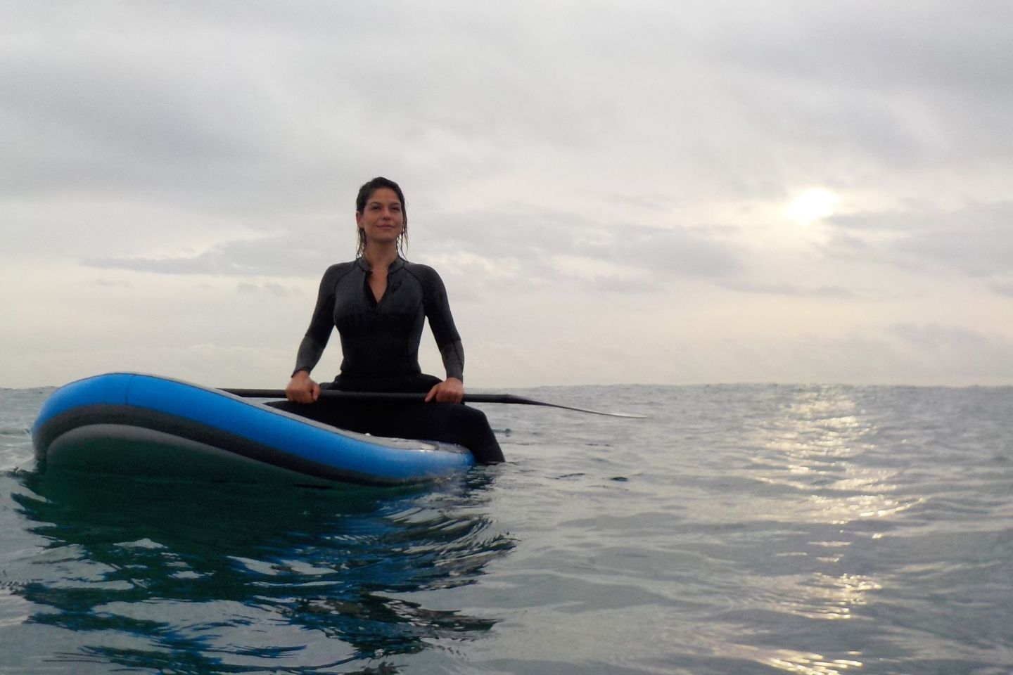 A woman in a wetsuit on a blue paddle board