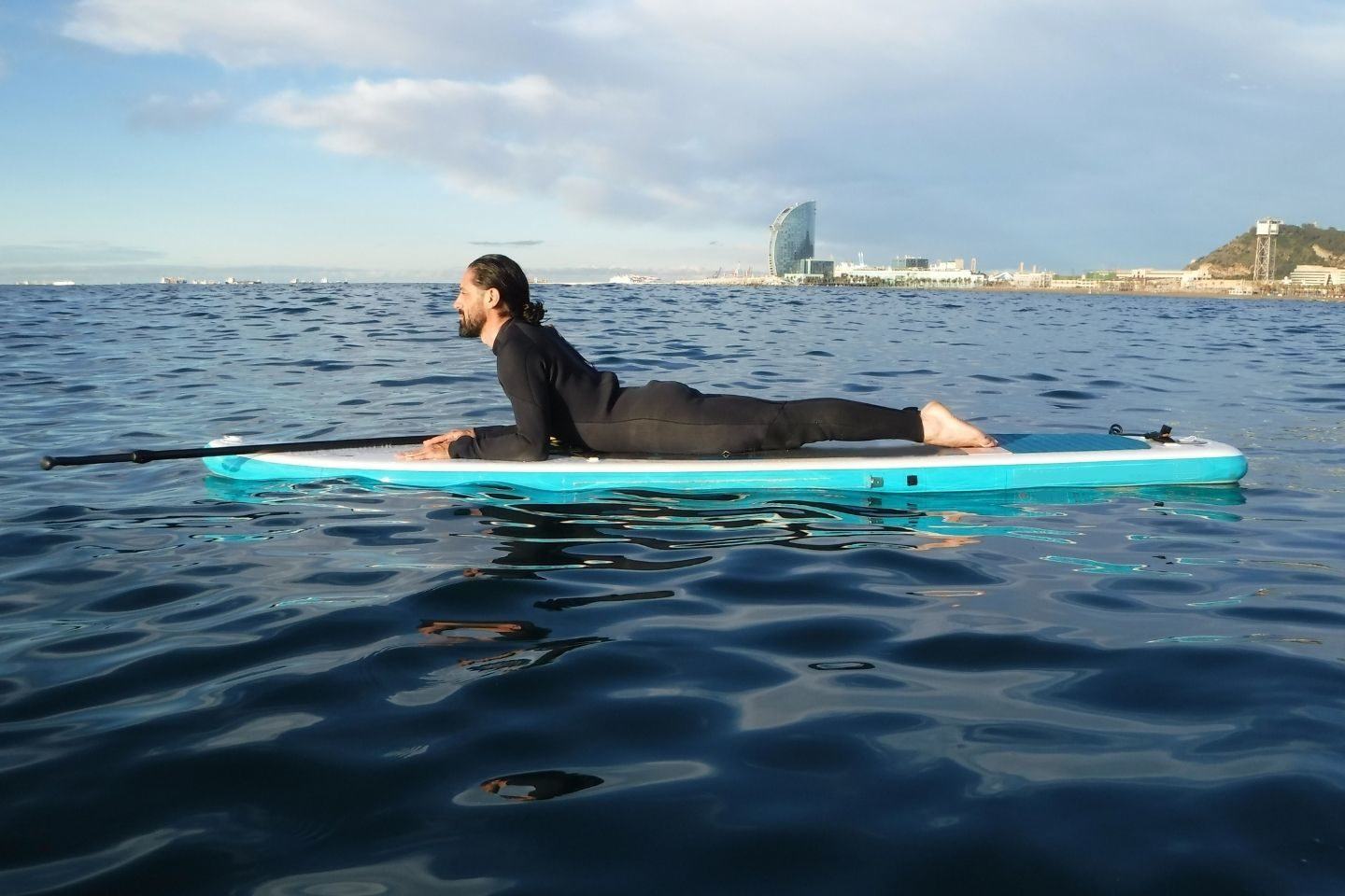 A man in a wetsuit on a blue paddle board