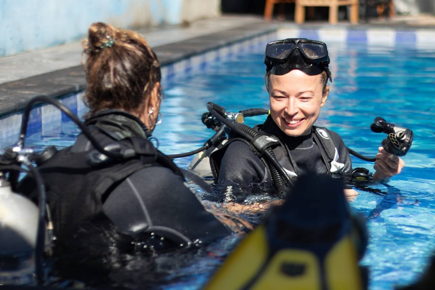 A woman getting experience with scuba diving under the guidance of experienced recreational diving instructor in swimming pool