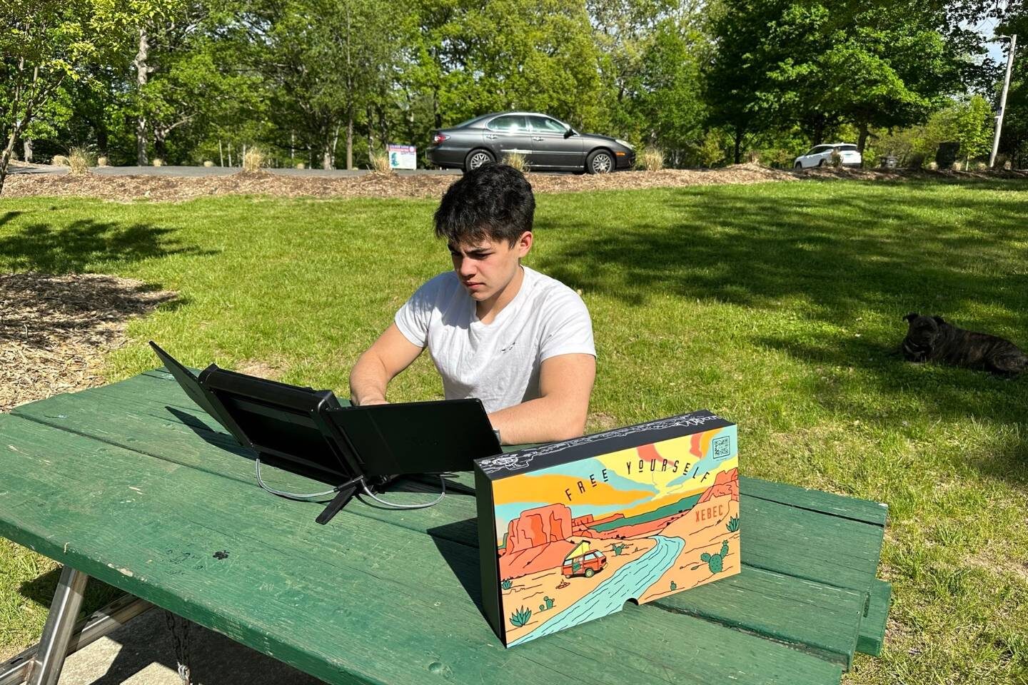 A man sitting at a picnic table while using Xebec Tri-Screen 2