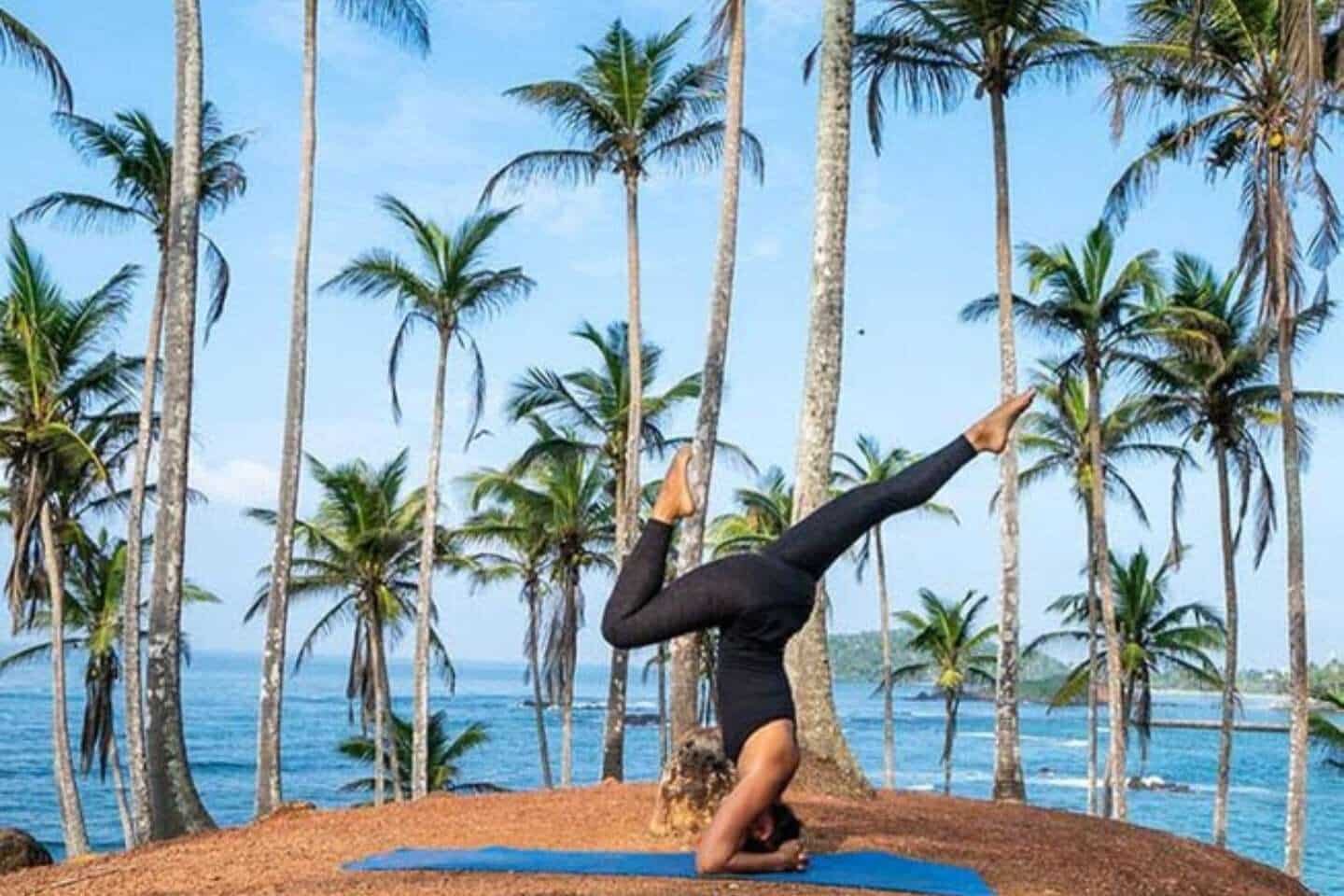 A woman during yoga amongst palm trees and the ocean in Sri Lanka