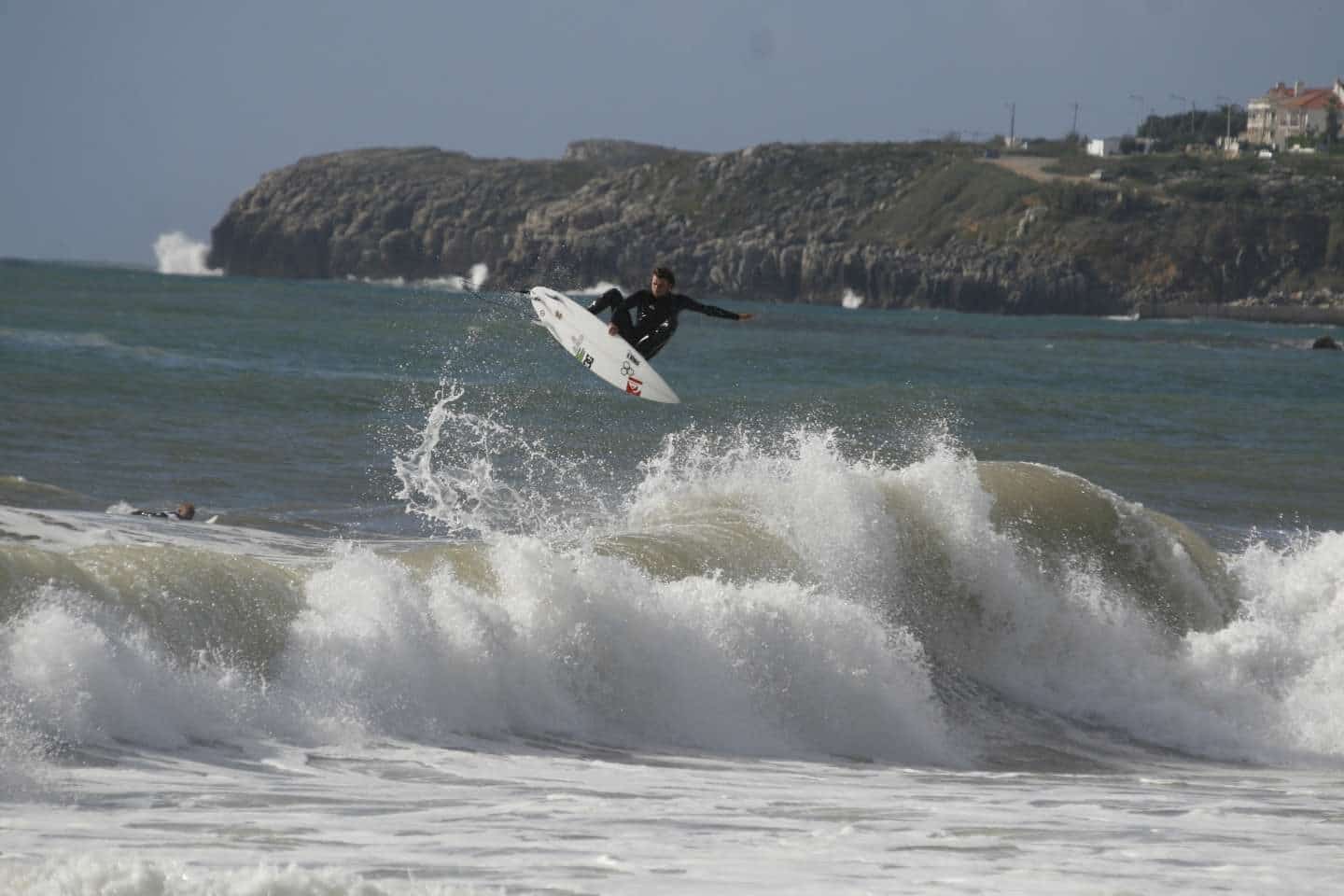 A surfer riding a large wave at a beach in Peniche, Portugal
