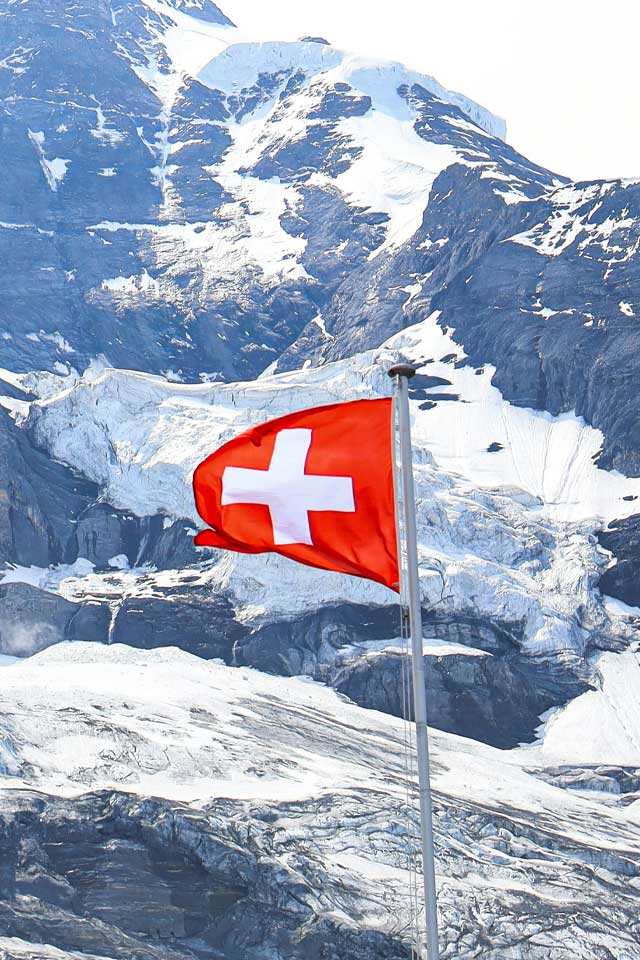 a swiss flag with snowy views in the background